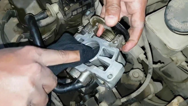 Mechanik čistí karburátor v motorovém prostoru.