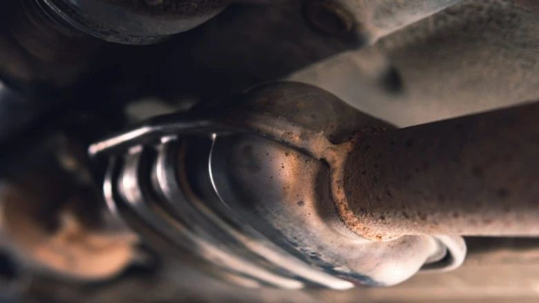 Zrezaný pohled na zkažený výfukový systém automobilu.