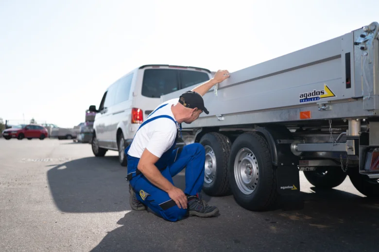 Muž kontroluje pneumatiku přívěsu pro nákladní automobil.