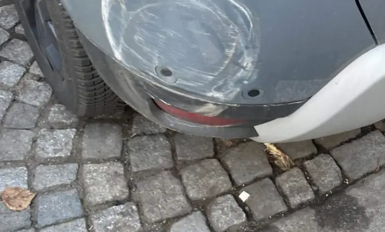 Škrábnutí na zadním nárazníku auta s bílým zbytkem po čištění.