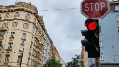 Červená světla na semaforu s dopravní značkou STOP u křižovatky.