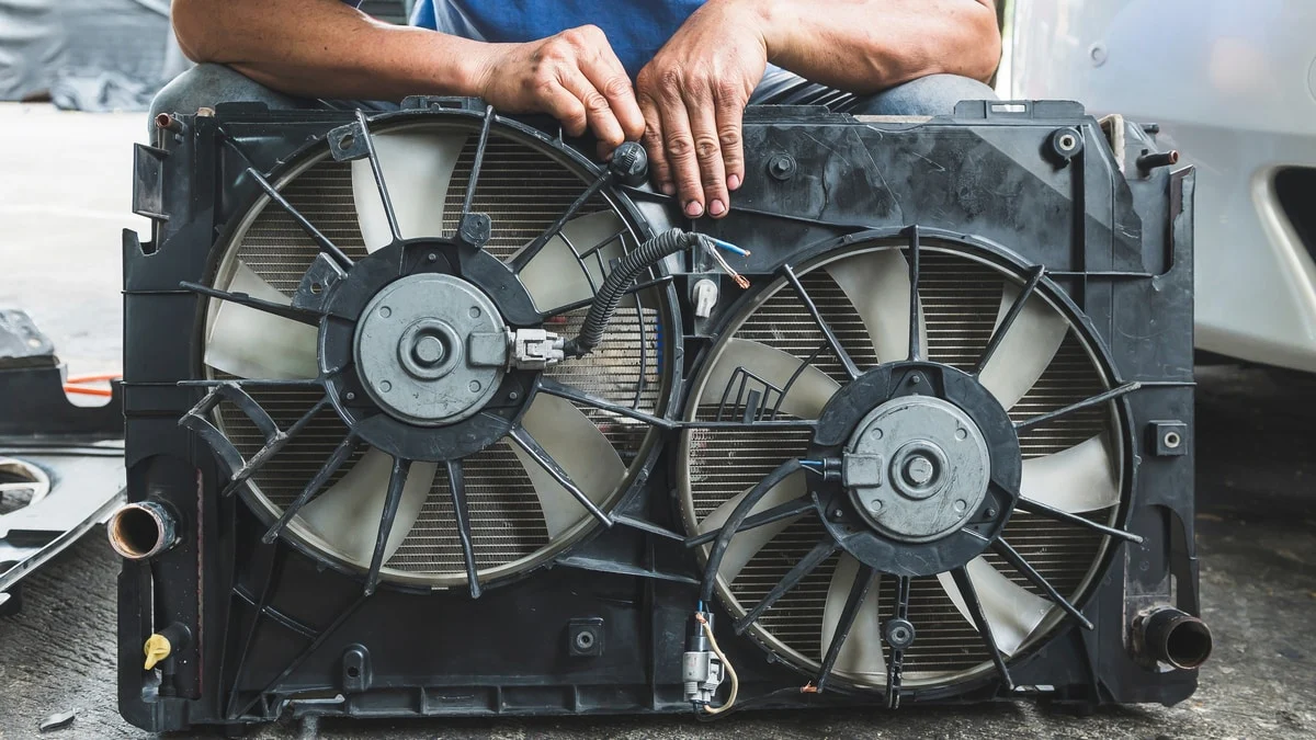 Mechanik drží chladič s ventilátory pro studený motor.