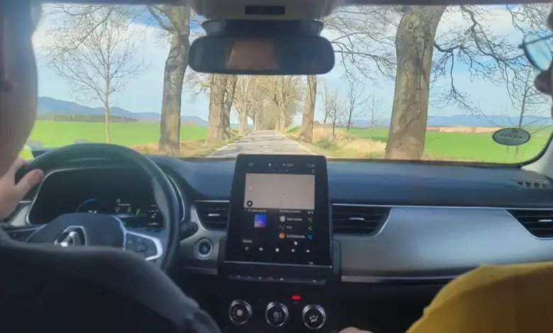 Vnitřek auta s navigací na displeji při jízdě po silnici.
