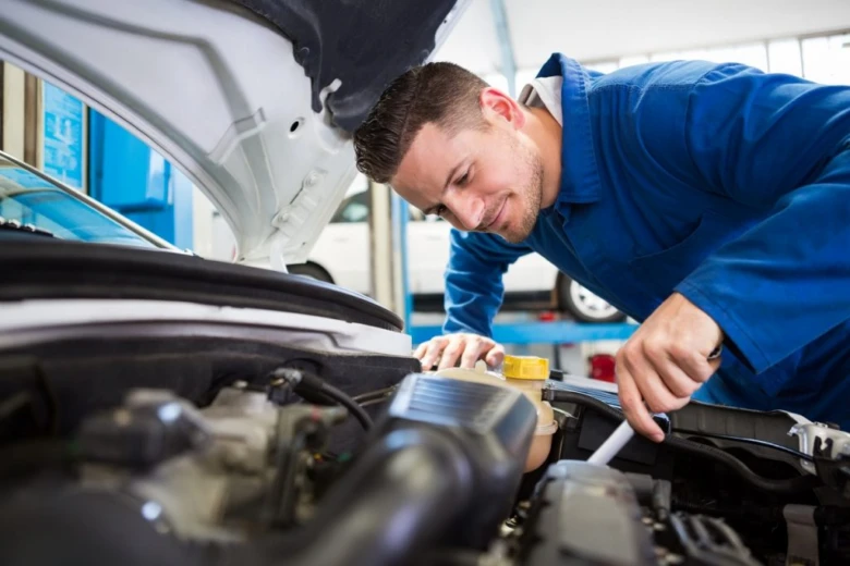 Mechanik opravuje motor vozu v dílně.