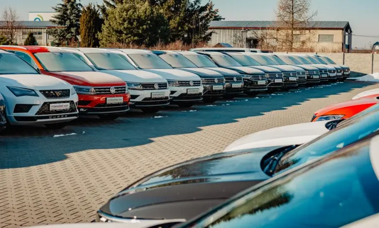 Řada nových osobních automobilů v prodejně aut venku.