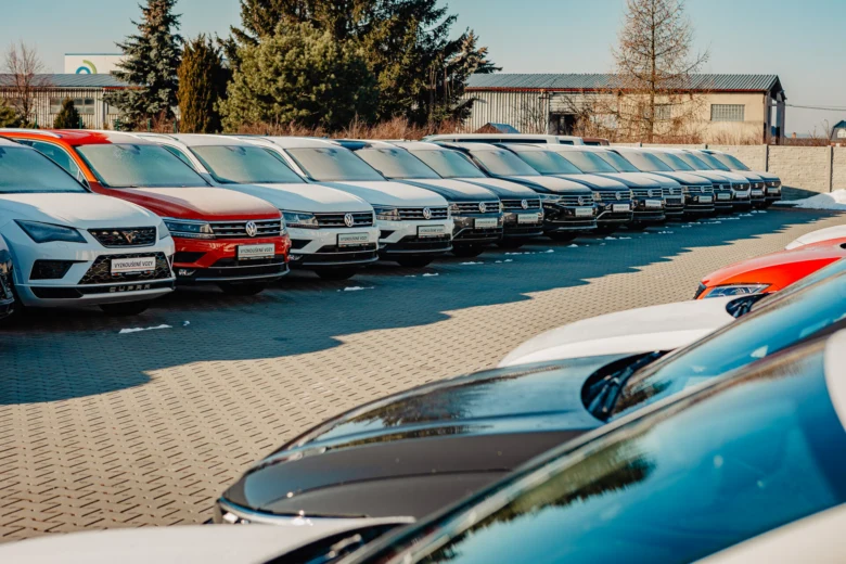 Řada nových osobních automobilů v prodejně aut venku.
