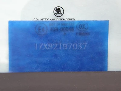 Modré autosklo s viditelnými značkami a certifikáty na zadní straně.