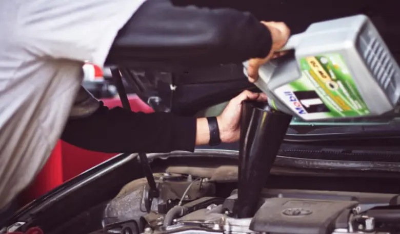 Person pouring coolant into car engine