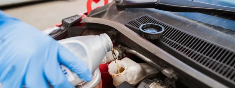 Nalévání chladicí kapaliny do zásobníku v motoru vozu.