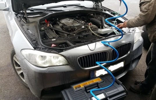 Čištění vstřikovačů auta pomocí přenosného zařízení pod kapotou.