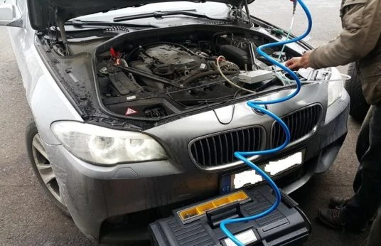 Mechanik čistí motor vozu pomocí modrých hadic.