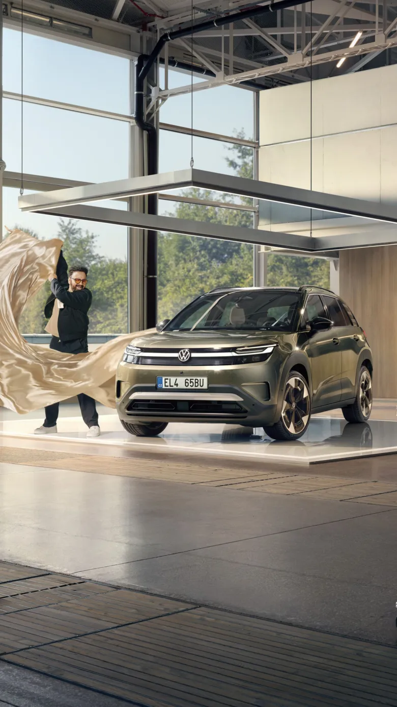 Muž odhaluje nový elektrický VW SUV v moderním showroonu.