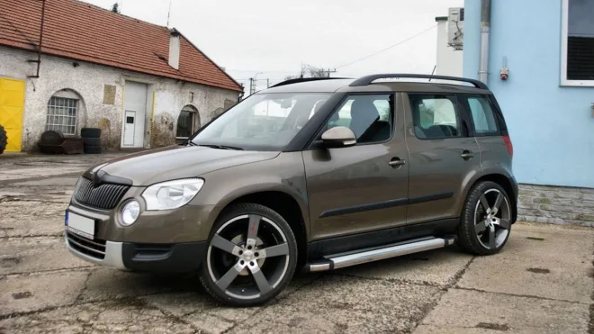 Hnědý SUV automobil zaparkovaný na asfaltu před budovami.