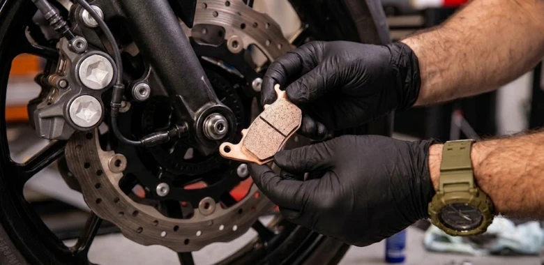 Mechanik drží nové brzdové destičky u kotouče při výměně.