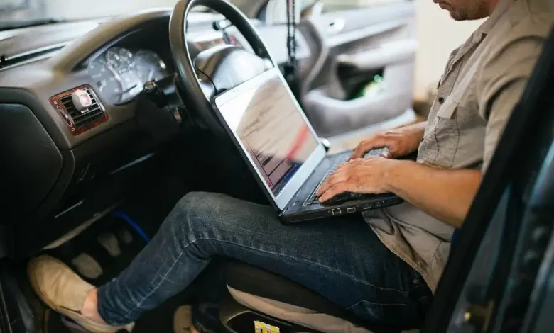 Mechanik v autě používá notebook pro dekódování chybových kódů přes OBD2.