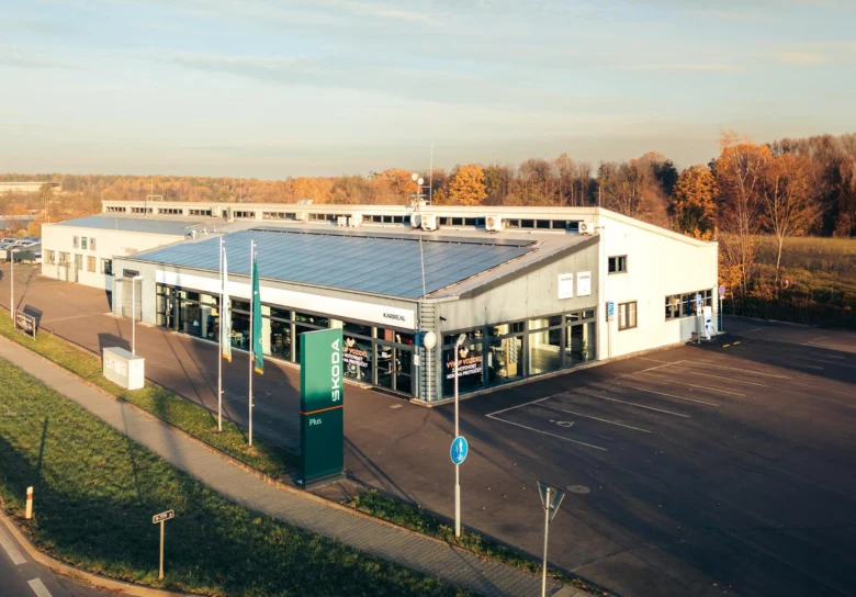 Exteriér autoservisu s mytím motoru v pozadí.