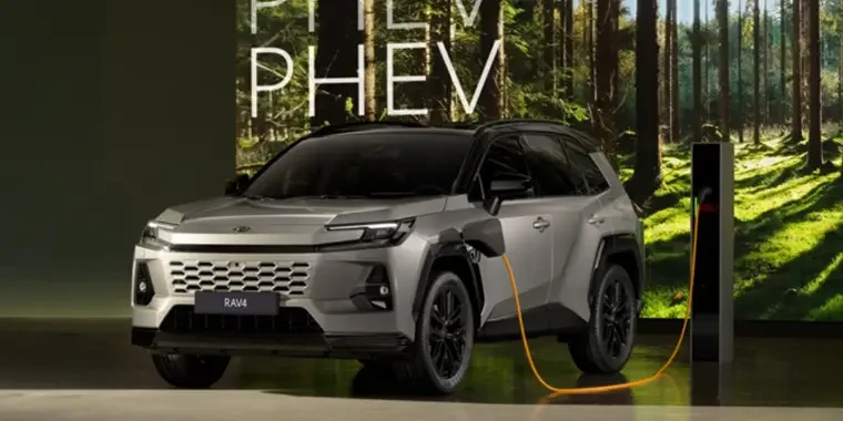 Stříbrná hybridní Toyota RAV4 nabíjená na stanici.