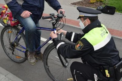 Policiista kontroluje jízdní kolo cyklisty na ulici.