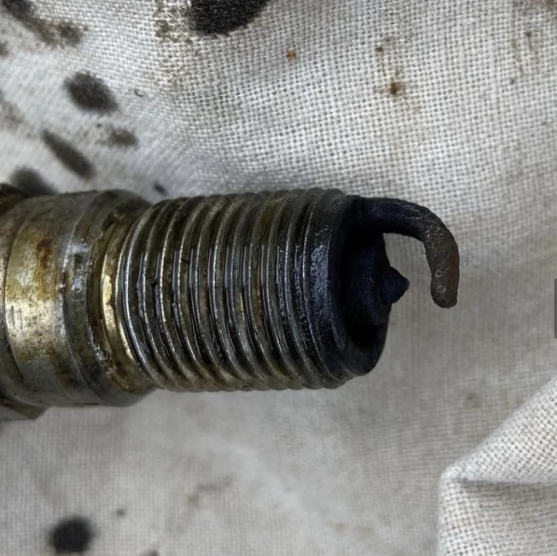 Použitá žhavící svíčka s ohnutým elektrodovým hrotem.
