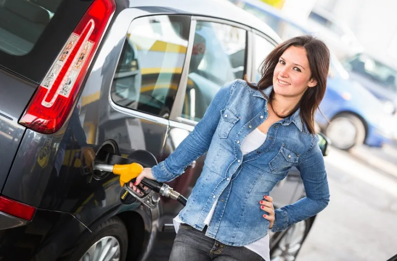 Žena v džínové bundě naplňuje své auto na benzínce.
