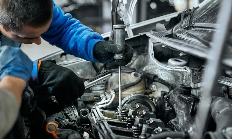 Mechanik odšrouvává žhavicí svíčku z motoru auta.