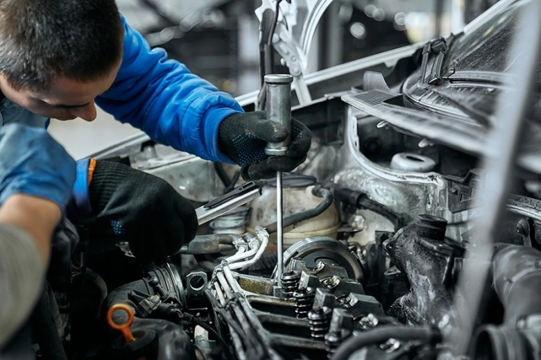 Mechanik odšrouvává žhavicí svíčku z motoru auta.