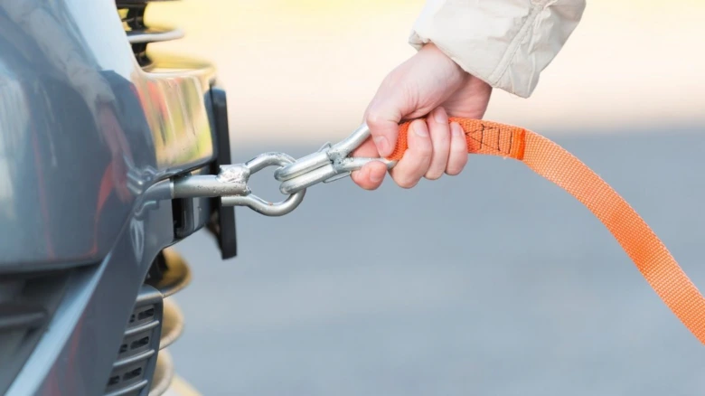 ruka připojuje oranžový tahač k nárazníku automobilu