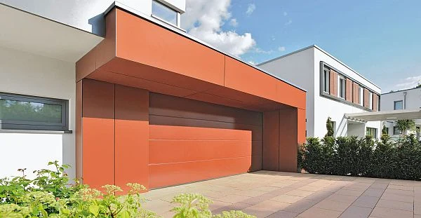 Moderní dům s oranžovými automatickými garážovými vraty.