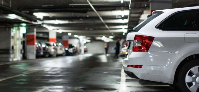 Bílý automobil zaparkovaný v podzemním parkovišti bez vnější pomoci.
