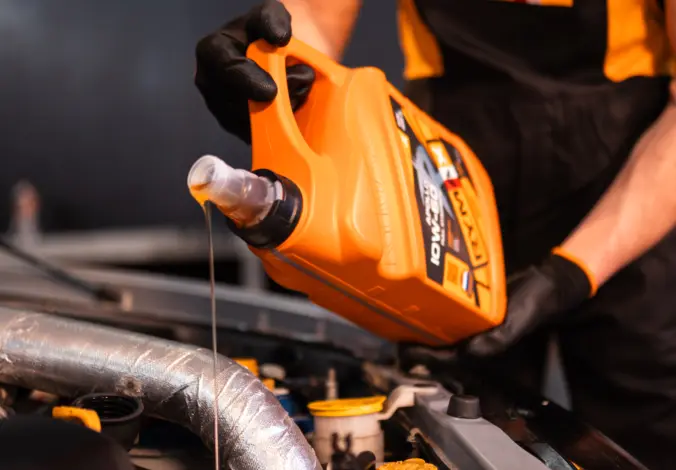 Mechanik nalévá motorový olej do automobilu