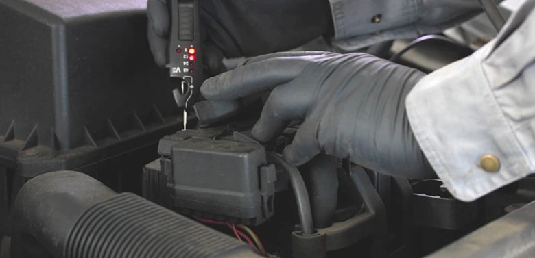 Technik testuje zapalovací cívku multimetrem v motorovém prostoru.