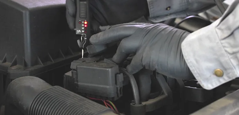 Technik měří odpor cívky zapalování multimetrem v motoru.