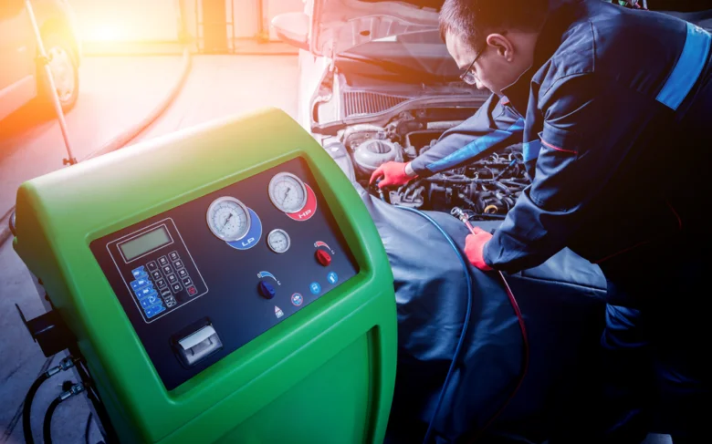 Technik čistí autoklimatizaci pomocí profesionálního zařízení pod kapotou auta.