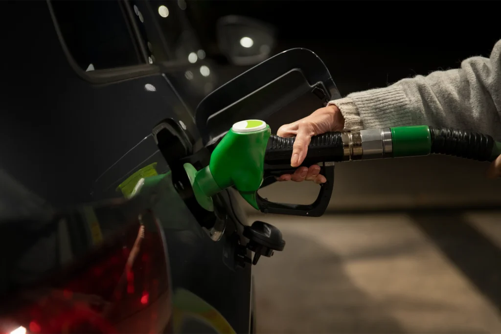 Osoba doplňuje palivo do automobilu noční benzínovou čerpací stanicí.