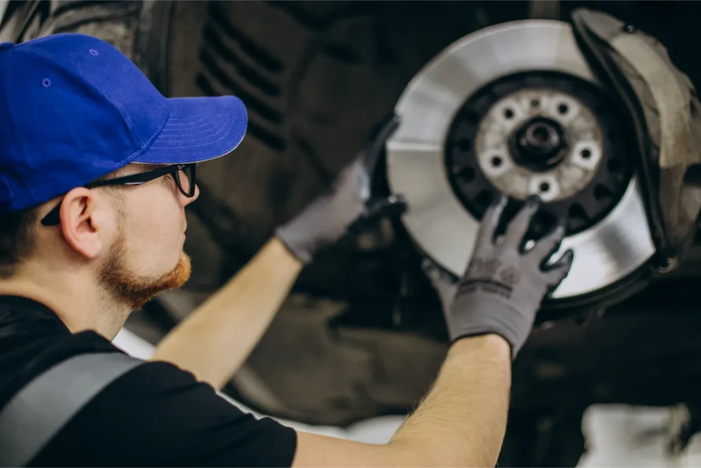Mechanik opravuje brzdný kotouč u auta v dílně.
