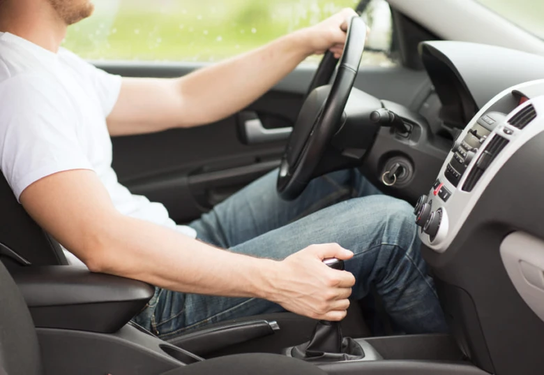 Muž řídí osobní automobil v dešti.