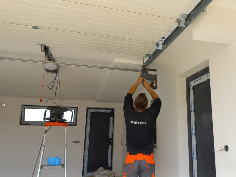 Technik montuje automatizované garážové brány pomocí elektrického nářadí.