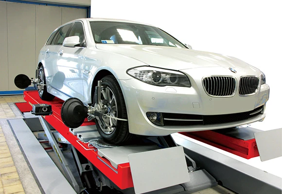 Bílý automobil na zvedací plošině pro seřízení kol.