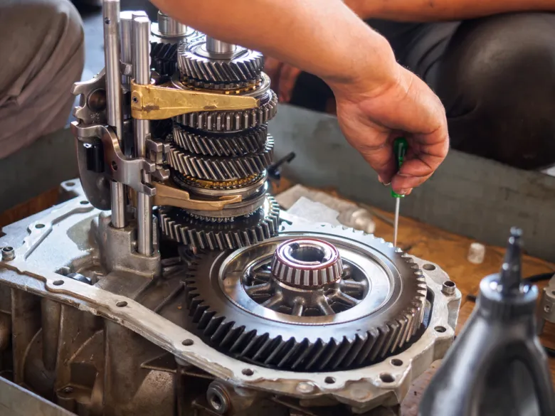 Mechanik sestavuje převody v manuální převodovce auta.