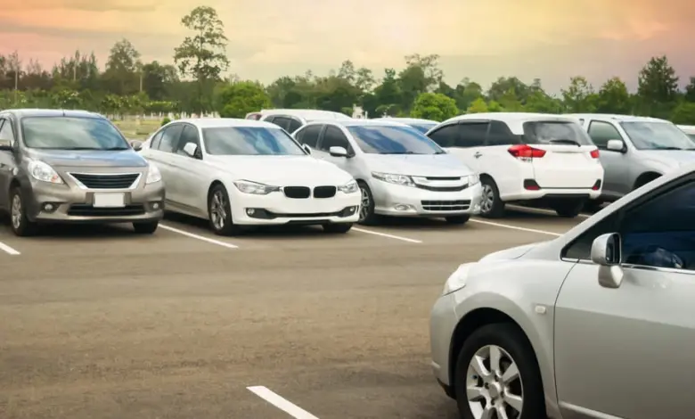 Různé osobní automobily zaparkované na parkovišti.