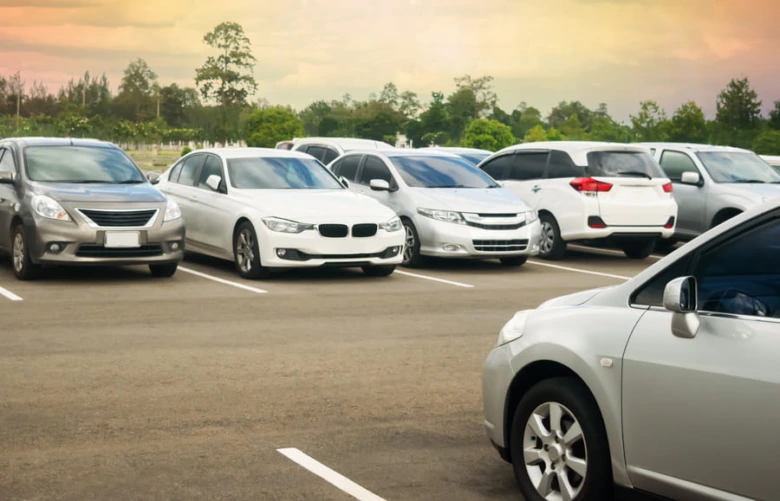 Různé osobní automobily zaparkované na parkovišti.