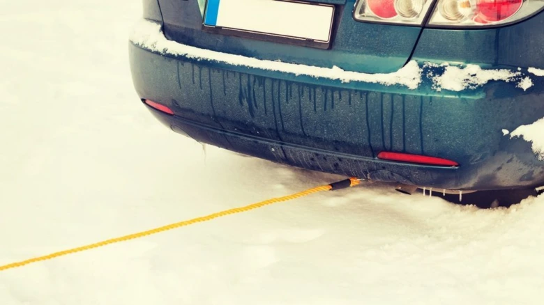 Modré auto v sněhu s lanem pro táhnutí.