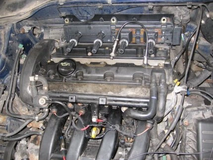 Motor automobilu s viditelnými komponenty pro měření komprese.
