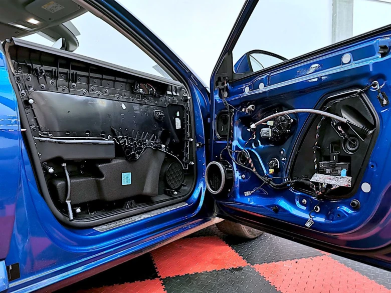 Modré auto s odmontovanými dveřmi ukazující vnitřní mechanismy.