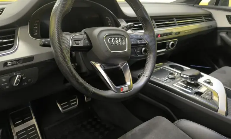 Interiér vozu s černým volantem značky Audi.