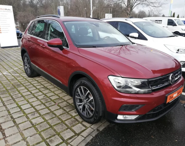 Červený VW Tiguan zaparkovaný na prodejním parkovišti.
