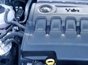 Motorový kryt vozu s viditelným logem v otevřeném motorovém prostoru.