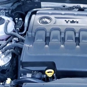 Motorový kryt vozu s viditelným logem v otevřeném motorovém prostoru.