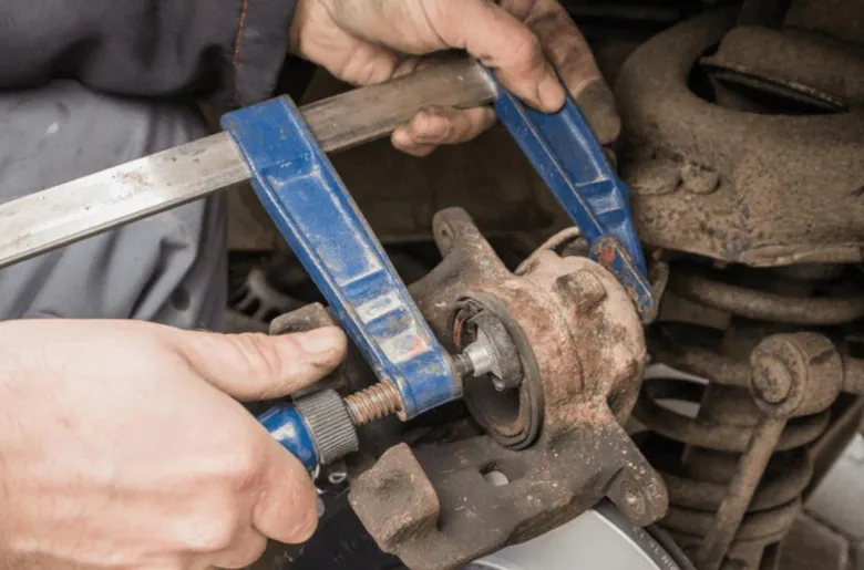Mechanik používá svěrák k vytažení pístu z brzdového třmenu.