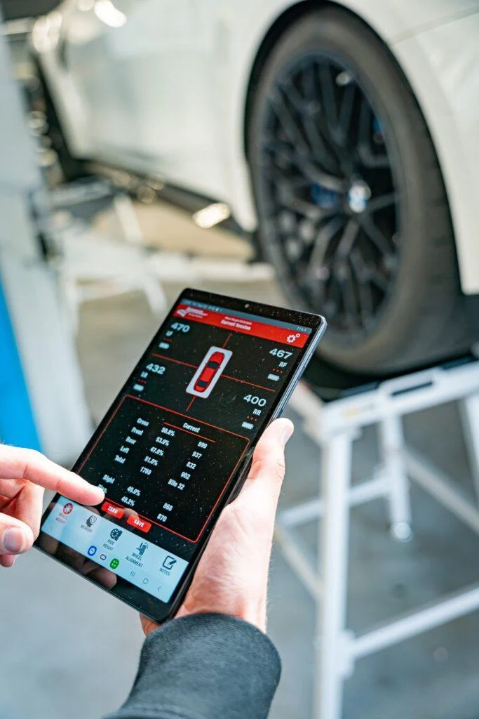 Technik nastavuje nastavení kol na tabletu pro automobil BMW.